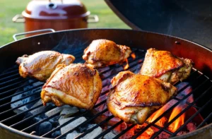 Juicy BBQ chicken thighs sizzling on a charcoal grill with visible flames and smoke, set in an outdoor environment.